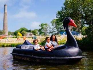Mother and children enjoying a ride on a black swan peddle boat